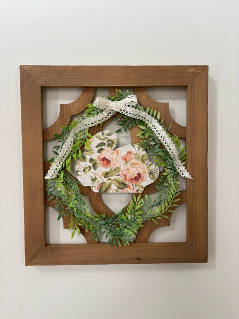 Decorative wreath with floral bunny and lace ribbon in a wooden lattice panel.