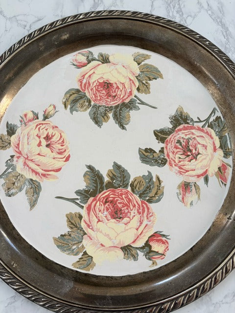 Round decorative tray with floral design on a marble surface
