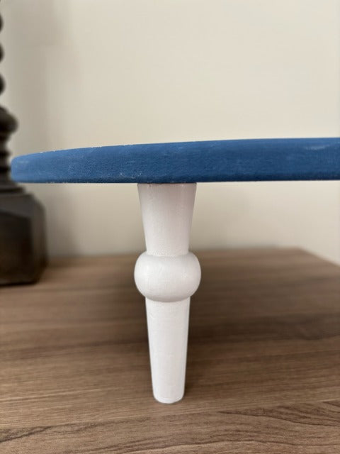 Small round riser with blue top and white base on a wooden surface