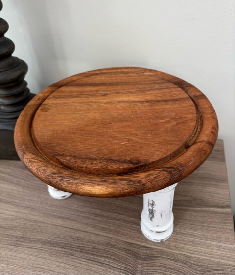 Wooden round riser with white legs on a wooden surface