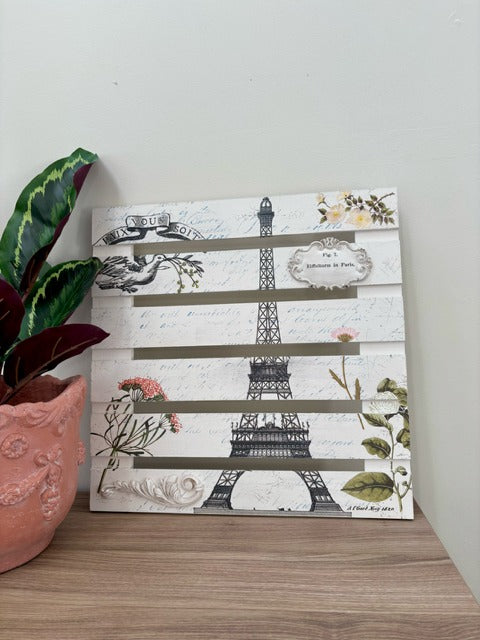 Decorative wall art with Eiffel Tower design on a wooden surface.