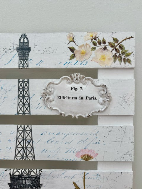 Decorative panel with Eiffel Tower, flowers, and text on a light gray background