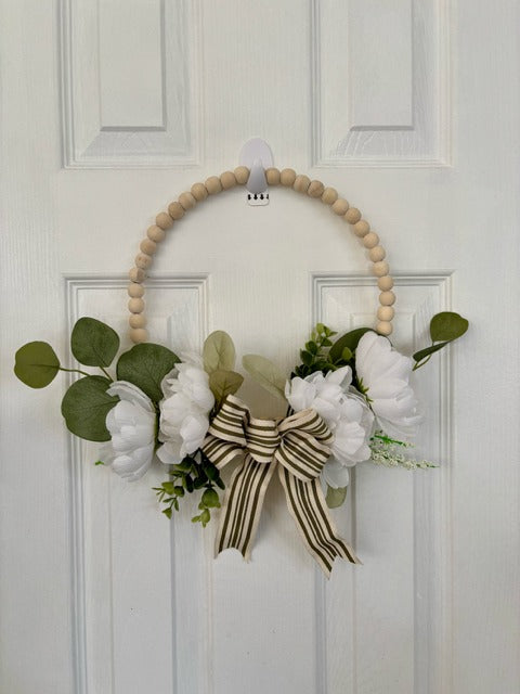 Decorative wreath with flowers and a bow on a white door