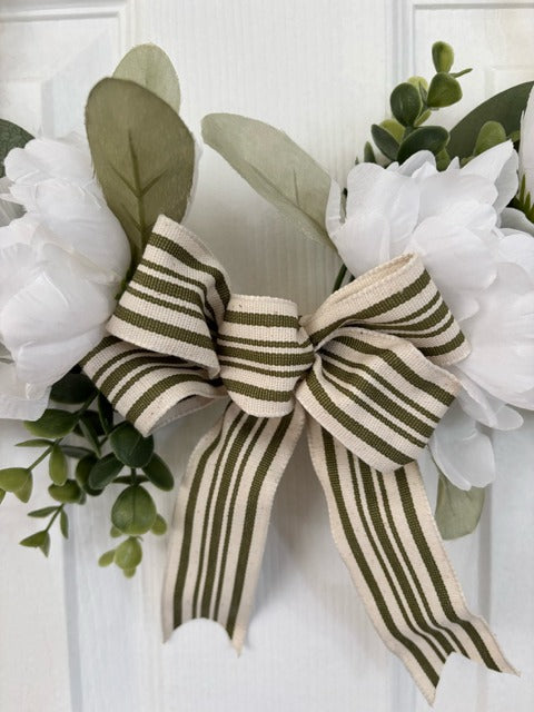 Decorative wreath with flowers and a bow on a white door