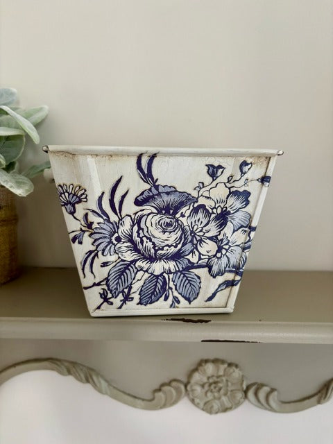 Decorative planter with blue floral design on a white surface