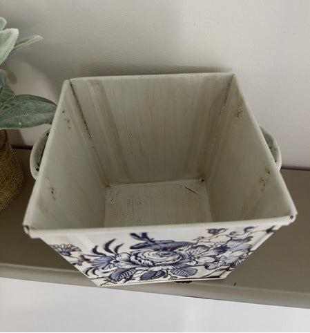Decorative storage basket with blue floral patterns on a shelf.