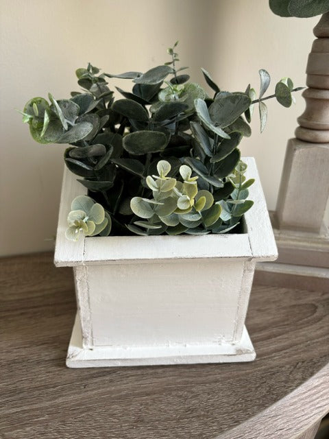 White birdhouse-shaped planter with greenery 