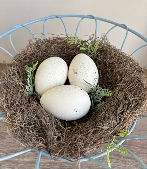 Decorative blue wire basket with a nest and eggs.
