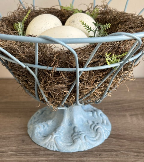 Decorative blue wire basket with a nest and eggs.