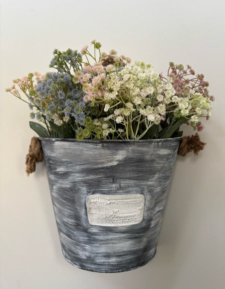 Decorative wall-mounted planter with flowers against a plain background