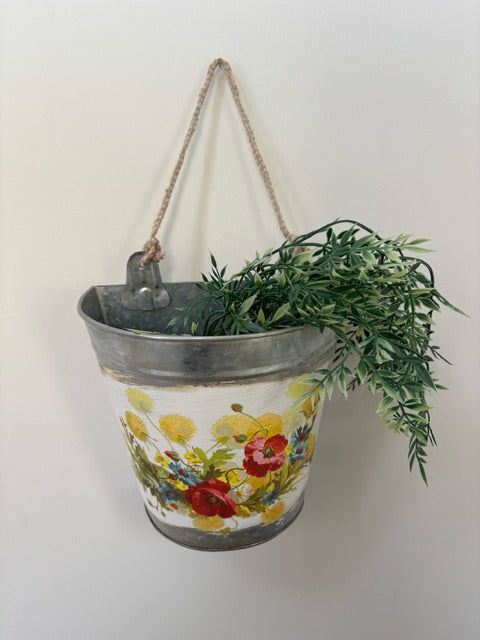 Decorative hanging planter with floral design on a white wall