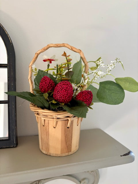Decorative basket with red raspberries and green leaves 