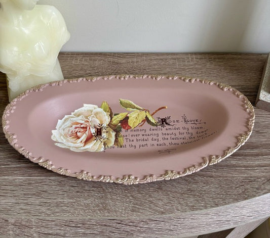 Decorative pink plate with floral design and text on a wooden surface