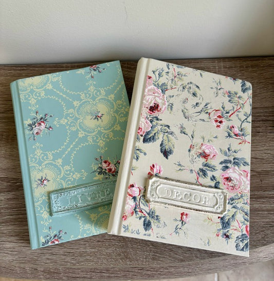 Two decorative books with floral patterns on a wooden surface