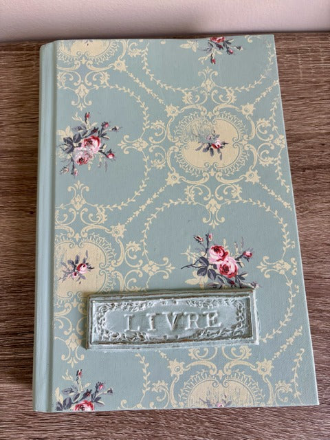 Decorative book with floral designs and 'Livre' embossing on a wooden surface