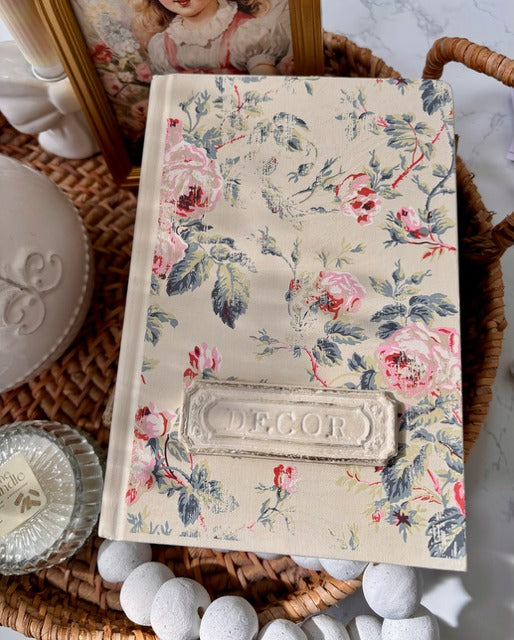 Floral-patterned book with 'Decor' embossed on it, placed on a textured surface.