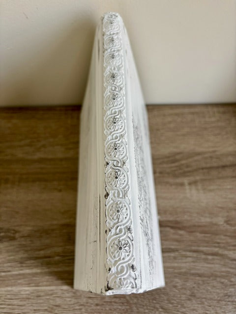 Decorative book with intricate white lace design on a wooden surface