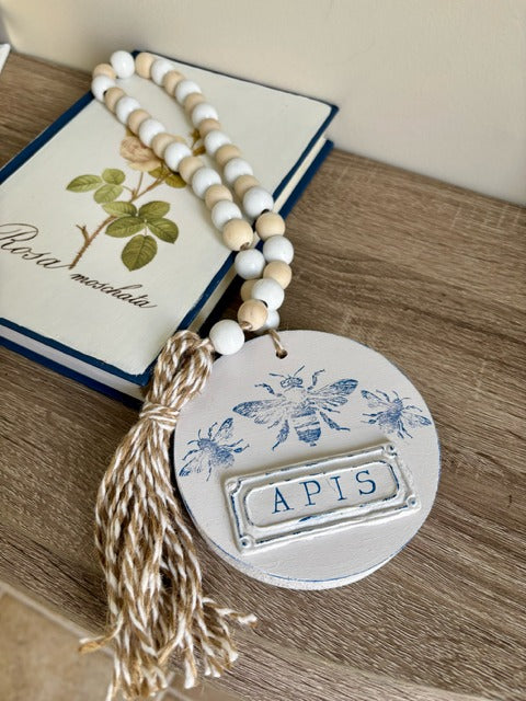 Decorative beaded garland with 'APIS' clay tag and bee design 