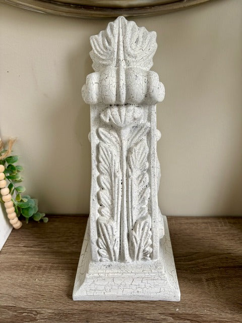 Decorative white corbel with intricate designs on a wooden surface.
