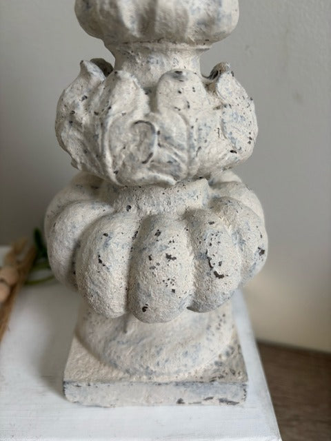 Decorative stone pedestal on a white surface with a neutral background