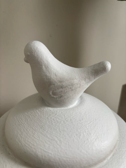 White ceramic jar with bird-shaped lid on a plain background