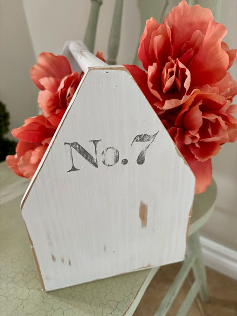 White wooden toolbox with 'No. 7' and coral flowers in the background