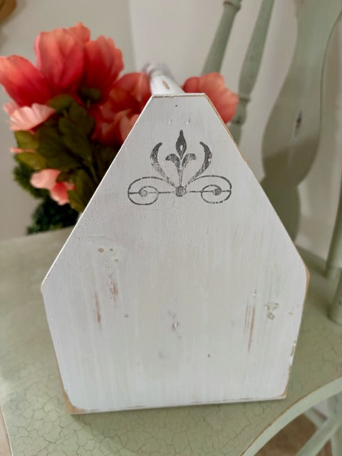 White wooden toolbox with decorative design on a surface with flowers in the background
