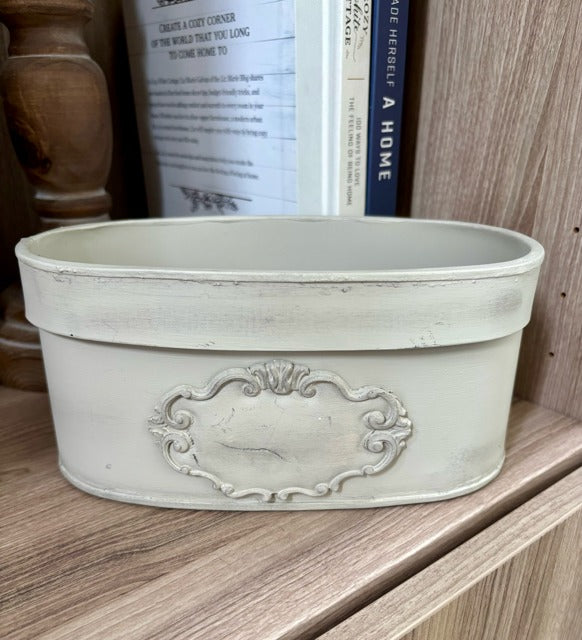 Decorative oval planter with intricate design on a wooden shelf