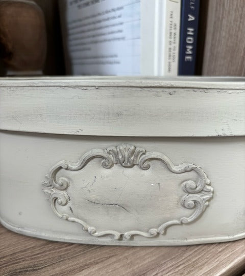 Decorative white metal box with intricate design on a wooden surface