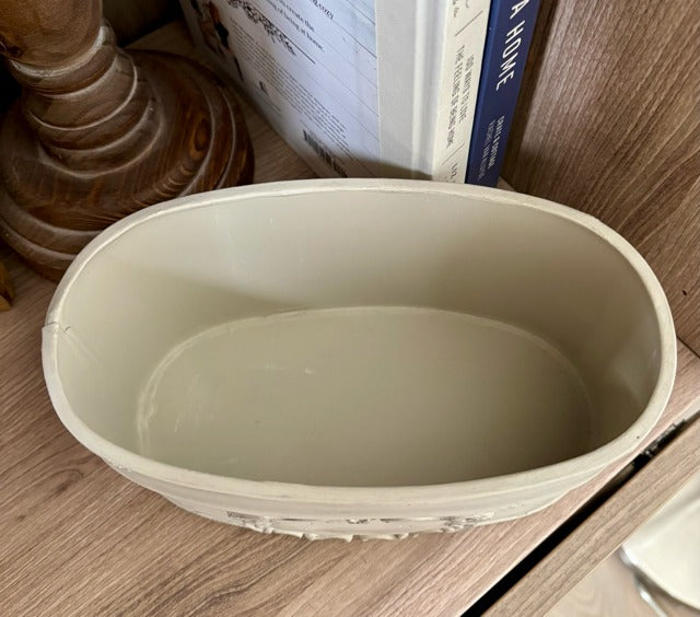 Beige metal container on a wooden surface with books in the background