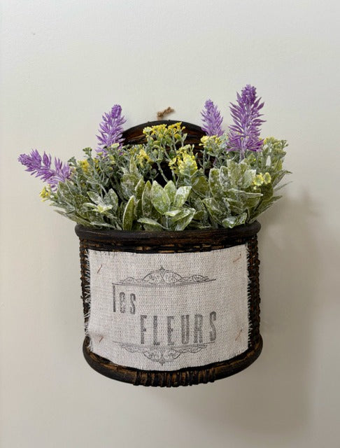 Decorative wall planter with artificial flowers labeled 'Les Fleurs' on a plain background