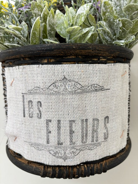 Decorative wall planter with artificial flowers labeled 'Les Fleurs' on a plain background