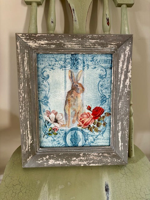 Framed artwork with a rabbit and roses on a textured surface