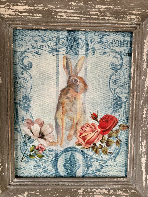 Framed artwork with a rabbit and roses on a textured surface