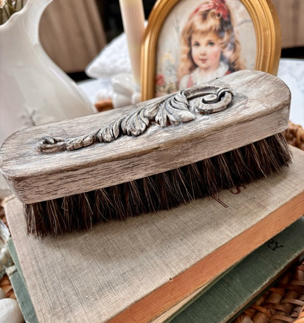 Vintage-style brush with decorative handle on a textured surface