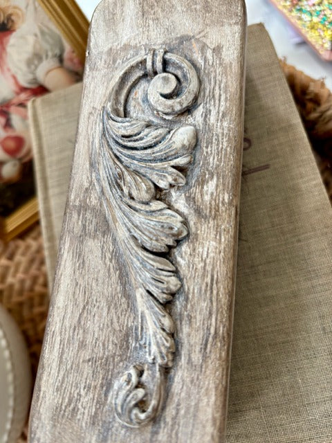 Decorative wooden brush with intricate mouldings on a textured surface