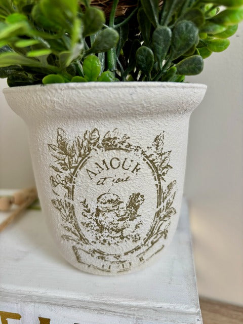 Decorative arrangement with greenery and a bird figurine in a white container.
