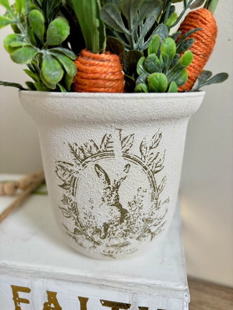 Decorative plant with carrots in a painted pot.