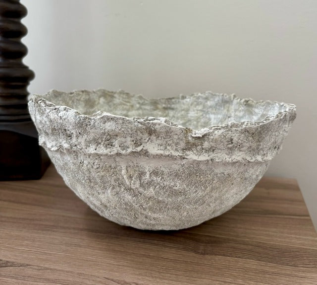 Decorative paper mache bowl on a wooden surface with a neutral background
