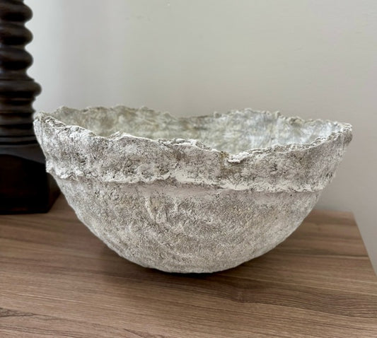 Decorative paper mache bowl on a wooden surface with a neutral background