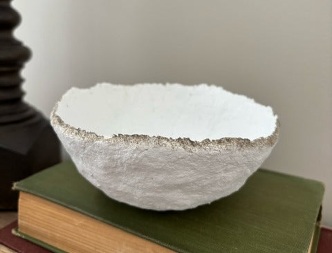 White textured bowl on a stack of books with a neutral background