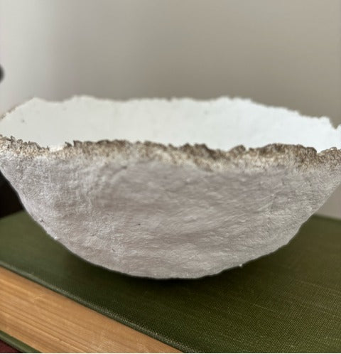 Textured paper mache bowl on a green surface with a neutral background
