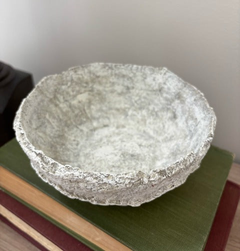 Textured  bowl on a stack of books with a plain background