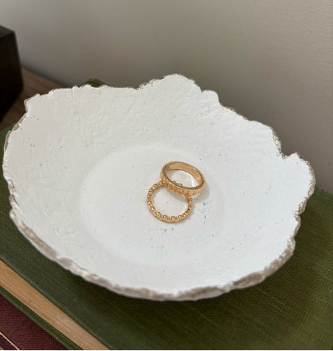 White textured paper mache dish with a gold ring on a green surface